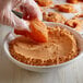 A gloved hand using J.O. Cajun Fry Mix to bread food in a bowl.