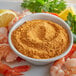 A bowl of shrimp and J.O. Seafood Seasoning with a lemon slice on the table.