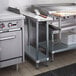 A Regency stainless steel filler table with a backsplash and undershelf on a counter in a professional kitchen.