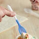 A hand holding a blue and white color-changing dessert spoon over a cup of ice cream.