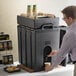 A man pouring a drink into a Cambro insulated beverage dispenser.