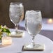 Two Schott Zwiesel Forte water goblets on a table with water and ice.