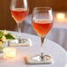 Two Schott Zwiesel wine glasses on a table with candles.
