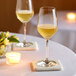 Two Schott Zwiesel Forte white wine glasses on a table with a candlelit centerpiece.