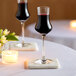 Two Schott Zwiesel wine glasses filled with Grappa on a table with a candle.