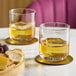 Two Schott Zwiesel old fashioned glasses of whiskey on a coaster.