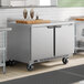 A stainless steel 48-inch dual temperature worktop refrigerator and freezer unit with two doors and casters.