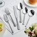 A close-up of a fork and knife on a white tablecloth.