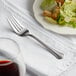 An Acopa stainless steel salad fork on a white plate with salad.