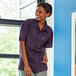 A woman smiling in a Uncommon Chef eggplant purple cook shirt.