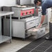 A man using a Beverage-Air 2 drawer chef base in a professional kitchen.