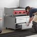 A woman opening a drawer in a Beverage-Air chef base in a professional kitchen.