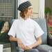 A woman wearing a white Uncommon Chef cook shirt with a mandarin collar sitting in a chair.