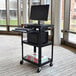 A Luxor black mobile computer cart with a laptop on it.