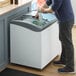 A man standing next to a Beverage-Air curved lid display freezer on a counter in a deli.