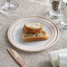 A white plastic plate with rose gold or copper bands, holding two pieces of bread, one with butter.