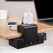 A Luxor KwikBoost EdgePower desktop charging station with a laptop and phone connected to it on a table.