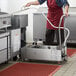 A man in a red apron using a Fryclone portable fryer oil filter machine on a counter.