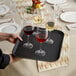 A person holding a Choice black non-skid serving tray with glasses of red and white wine.