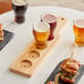 An Anchor Hocking Barbary Wood Flight Paddle holding beer glasses and sandwiches on a table.