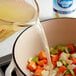 College Inn Chicken Broth being poured into a pot of food.