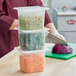 A woman cutting vegetables in a San Jamar translucent plastic food pan on a counter.