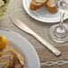 A Visions rose gold plastic knife on a plate with food.