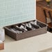 A Vollrath brown polypropylene tray with 4 compartments holding silverware.