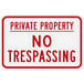A white rectangular aluminum sign with red text that says "Private Property / No Trespassing"