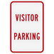 A white sign with red text that says "Visitor Parking" on it.