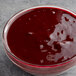 A bowl of Les Vergers Boiron blackberry puree on a table with a spoon.