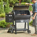 A man cooking meat on a Backyard Pro wood-fired pellet grill.