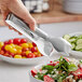 A person using GET stainless steel salad tongs to serve salad