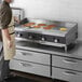 A man in an apron cooking pancakes on a Cooking Performance Group countertop griddle.