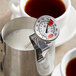 A Cooper-Atkins frothing thermometer in a cup of brown liquid.