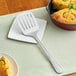 A GET slotted spatula on a plate of food.
