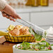 A person using GET stainless steel comb salad tongs to serve salad