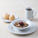 A Tuxton Alaska china bowl filled with grapefruit on a table with a bowl of cereal and a cup of coffee.