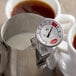 A Cooper-Atkins frothing thermometer in a metal container of coffee.
