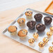 A Chicago Metallic bakery display tray with muffins and cupcakes on a counter.