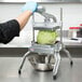 A person using a Nemco Easy Lettuce Kutter to slice lettuce into a bowl.