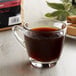 A glass cup of coffee with a bag of Crown Beverages Emperor's Finest Decaf Coarse Ground Coffee.