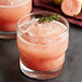 A glass of Les Vergers Boiron Pink Guava puree with ice and a sprig of thyme.