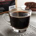 A glass cup of Crown Beverages Royal Reserve Guatemalan Coarse Ground Coffee on a table.