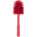 A close-up of a red Carlisle Sparta multi-purpose cleaning brush with long bristles.