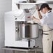 A woman in a black hat using an Estella spiral dough mixer to mix food.