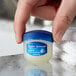 a hand holding a small container of lip balm