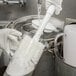 A person washing dishes in a sink with a Carlisle white multi-purpose cleaning brush with white bristles.