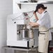 a person in a white apron pouring something into a bowl