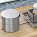 A brushed stainless steel lid on a container on a table.